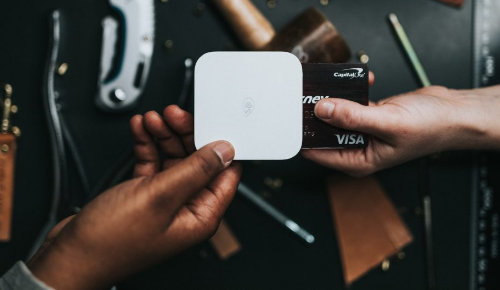 one person holding card machine with other holding card