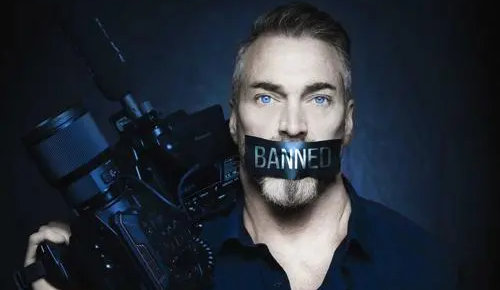 Mikki Willis holding video camera and mouth taped with the words banned