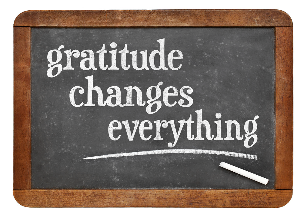 The sign features a chalkboard background with handwritten text that says, Gratitude changes everything.